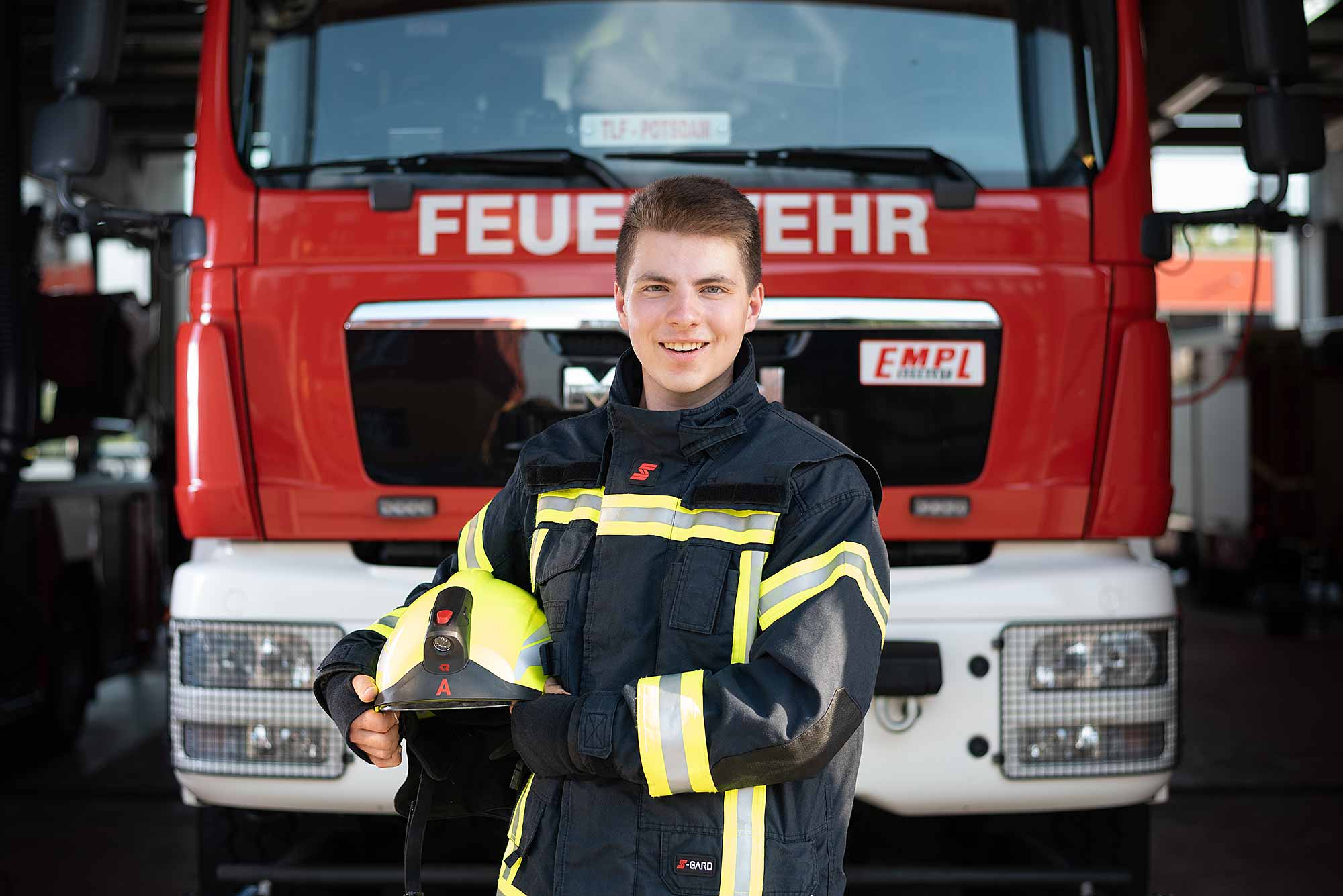 © Thilo Gögelein Fotografie // Feuerwehrmann der Feuerwehr Potsdam in Einsatzkleidung vor Feuerwehrfahrzeug