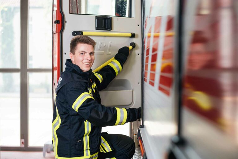 © Thilo Gögelein Fotografie // Feuerwehrmann der Feuerwehr Potsdam in Einsatzkleidung vor Feuerwehrfahrzeug